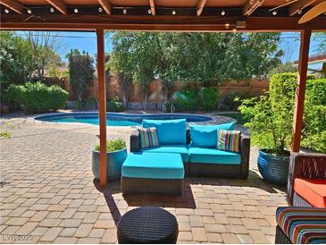 Inviting covered brick patio seating area with a plush blue cushioned sofa overlooking the sparkling pool at 2809 Gilmary Ave, Las Vegas, NV 89102