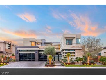 Contemporary two-story home boasts a sleek design with a glass garage door and desert landscaping at 4208 Lapis Ridge Ct, Las Vegas, NV 89135