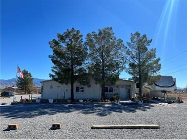 Charming single story home with desert landscaping, mature trees, and long driveway on a sunny day at 4861 Pahrump Valley Blvd, Pahrump, NV 89048