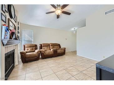 Inviting living room featuring neutral colors, tile floors, and a cozy fireplace at 6982 Rusty Nail Way, Las Vegas, NV 89119