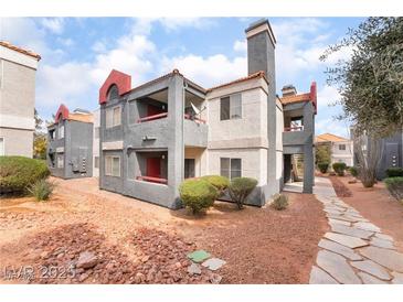 Inviting condo featuring a charming, red-trimmed exterior, balcony, and desert landscaping at 8600 W Charleston Blvd # 1043, Las Vegas, NV 89117