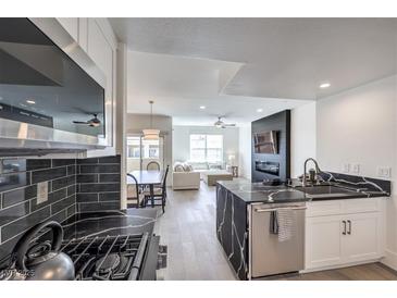 Modern kitchen with black and white finishes that flow into an open concept living and dining area at 8777 W Maule Ave # 3090, Las Vegas, NV 89148