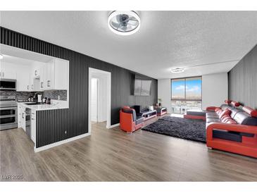 Spacious living room featuring a modern black and red sectional sofa, city views, and sleek wall accents at 3930 University Center Dr # 909, Las Vegas, NV 89119