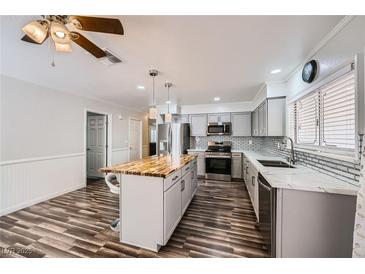 Bright kitchen featuring stainless appliances, stylish island with seating, and modern light fixtures at 6710 Redwood Cir, Las Vegas, NV 89103
