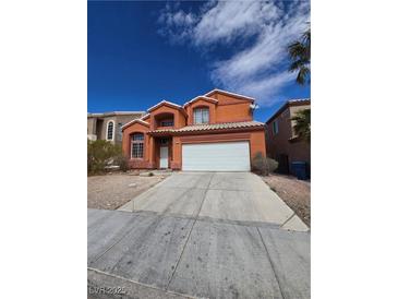 Charming two-story home with orange stucco exterior and a two car garage on a sunny day at 8124 Kokoma Dr, Las Vegas, NV 89128