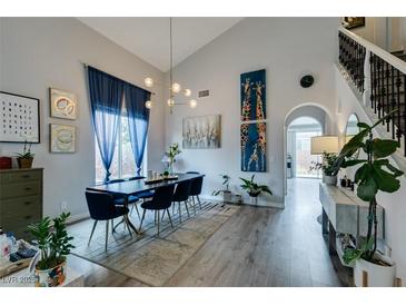 Bright dining room featuring hardwood floors, high ceilings, and stylish modern lighting fixture at 11769 Via Vera Cruz Ct, Las Vegas, NV 89138