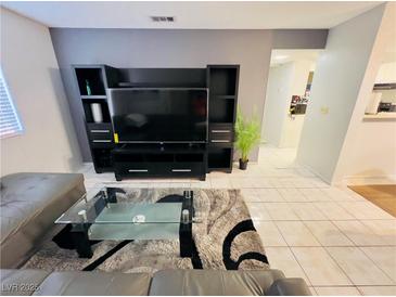 Living room featuring a large television with black stand and grey tile flooring at 6750 Del Rey Ave # 133, Las Vegas, NV 89146