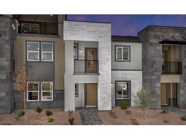 Modern townhome showcasing gray stone and stucco exterior with multiple windows and small landscaped front at 883 Apatite Pl # Lot 57, Henderson, NV 89011