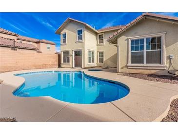 Backyard with pool features sparkling water, and home with large windows and a tan-colored exterior at 5861 Lakeland Village Dr, North Las Vegas, NV 89081