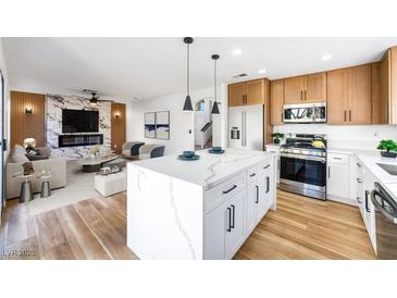 Open-concept living space with a modern kitchen, fireplace, and comfortable seating area at 7832 Desert Candle Way, Las Vegas, NV 89128