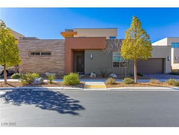 Modern home featuring a stylish facade with mixed materials, desert landscaping, and a two-car garage at 10879 Artesano Ave, Las Vegas, NV 89135