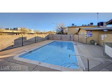 Community pool with a metal fence and clean blue water on a sunny day at 3821 1/2 Daisy St # 25, Las Vegas, NV 89119