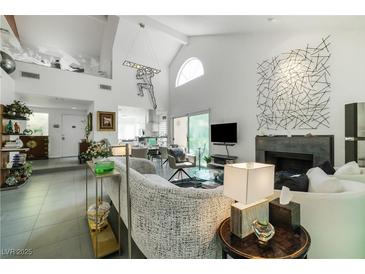 Bright living room featuring vaulted ceilings, modern art, and a cozy fireplace for a luxurious living space at 6923 Emerald Springs Ln, Las Vegas, NV 89113