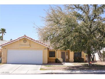 Charming single-story home featuring a two-car garage and well-maintained front yard with mature tree at 7405 Painted Ridge St, Las Vegas, NV 89131