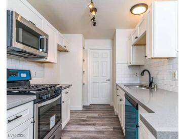 Galley kitchen featuring white cabinets, subway tile backsplash, and stainless steel appliances at 2200 S Fort Apache Rd # 2023, Las Vegas, NV 89117