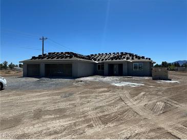 New home construction featuring a three-car garage and shingled roof on a spacious lot at 331 Huracan St, Pahrump, NV 89048
