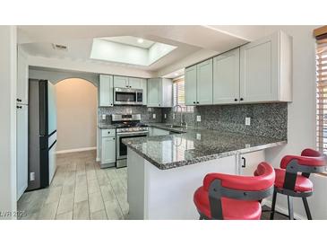 Charming kitchen features gray cabinets, granite counters, and a skylight for natural light at 508 Indian Princess Dr # 104, Las Vegas, NV 89145