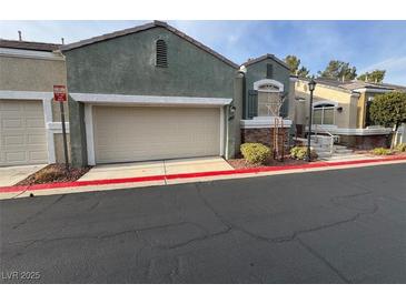 View of a two-car garage and the front of a home with stone accents and mature landscaping at 9126 Haddington Ln, Las Vegas, NV 89145