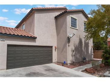 Tan two-story home with a two car garage, red tile roof, and minimal landscaping at 7940 Violet Dawn St, Las Vegas, NV 89149