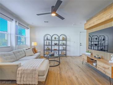 Bright living room features a plush sofa, sleek ceiling fan, and modern shelving for stylish storage at 10768 Ditchburn Ct, Las Vegas, NV 89166