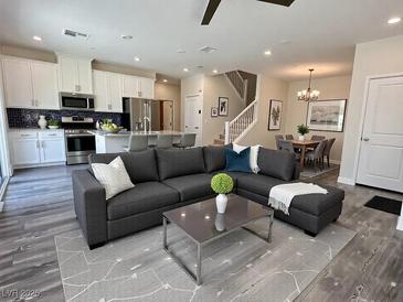Bright living room open to dining and kitchen, features modern gray sofa and updated flooring at 545 Thea St # 1315, Henderson, NV 89052