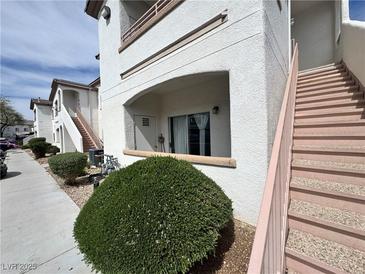 Exterior angle of a multi-level condo with stairs and a sidewalk with green bushes and a door on the first level at 5650 E Sahara Ave # 1035, Las Vegas, NV 89142