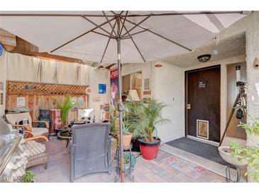 Inviting outdoor patio area with comfortable seating and a large umbrella for shade at 775 Cathy Ln, Henderson, NV 89015