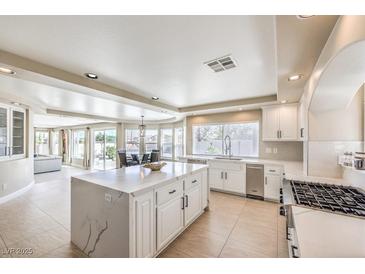 Bright kitchen features an island with white cabinets, tile flooring, and stainless steel appliances at 11072 Pentland Downs St, Las Vegas, NV 89141