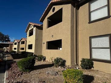 Exterior view of a multi-unit building with tan siding and landscaped grounds at 2451 N Rainbow Blvd # 1156, Las Vegas, NV 89108