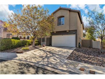Inviting two-story home featuring a well-kept lawn, mature tree, and attached two-car garage at 9768 Northern Dancer Dr, Las Vegas, NV 89117