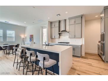 Bright kitchen features an island with bar seating, stainless steel appliances, and light gray cabinetry at 10239 Meandering Dell Ave, Las Vegas, NV 89166