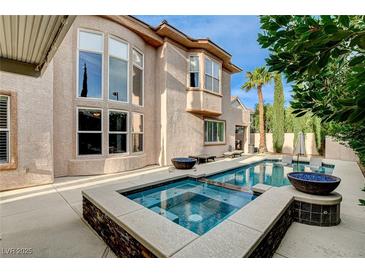 Beautiful backyard pool and spa with lounge chairs, palm trees, and privacy landscaping at 10671 Capesthorne Way, Las Vegas, NV 89135