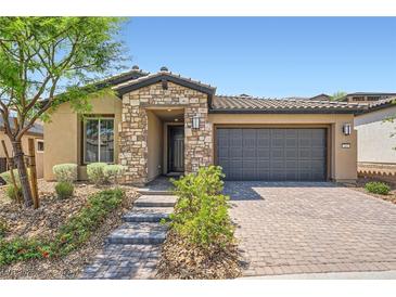 Charming single-story home featuring stone accents, low maintenance landscaping, and a brick paved driveway at 243 Sun Glaze Ave, Henderson, NV 89011