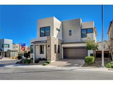 Modern two-story home with a two-car garage, stone accents, and beautiful landscaping against a bright blue sky at 513 Founders Creek Ave, North Las Vegas, NV 89084