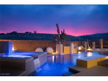 Inviting pool with water features, illuminated at night with colorful sunset skies in the background at 80 Glade Hollow Dr, Las Vegas, NV 89135