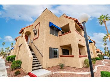 Attractive condo complex featuring a tan exterior, stairwell access, and beautiful desert landscaping at 4131 Gannet Cir # 389, Las Vegas, NV 89103
