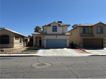 Two story home with blue garage door, desert landscaping, and light colored stucco at 6297 Peach Orchard Rd, Las Vegas, NV 89142