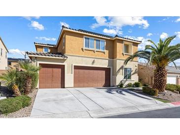 Stunning two-story home features a well-maintained yard, a dual-car garage, and a beautiful tan and brown exterior paint scheme at 1112 Adobe Creek Ct, North Las Vegas, NV 89084