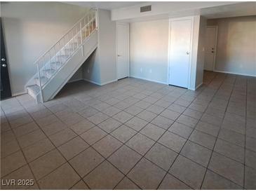 Bright living room features tile floors, staircase, and neutral paint at 3417 Civic Center Dr # B, North Las Vegas, NV 89030