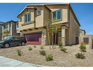Two-story home featuring a red two-car garage and desert landscaping at 10748 Wild Poppy Ave, Las Vegas, NV 89129