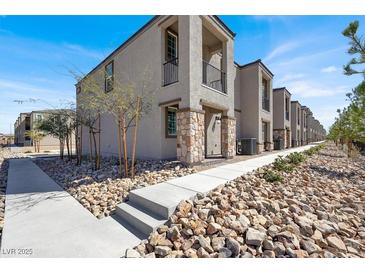 New townhome showcasing stone accents, a private balcony, and desert landscaping for low maintenance living at 5609 Steampunk St, Las Vegas, NV 89118