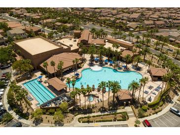 Stunning aerial view of community pool, clubhouse, palm trees, lounge chairs, and nearby homes at 677 Viale Machiavelli Ln, Henderson, NV 89011