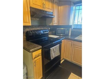 Traditional kitchen featuring wood cabinets, dark countertops, and modern black appliances at , Las Vegas, NV 89108