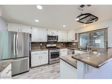 Bright kitchen with stainless steel appliances, white cabinetry and wood tile flooring at 263 Baring Cross St, Henderson, NV 89074