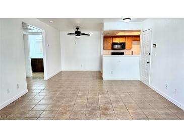 Bright living room features neutral tile flooring, and is adjacent to the kitchen with wood cabinets at 7100 Pirates Cove Rd # 1022, Las Vegas, NV 89145