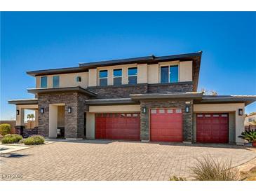 Contemporary two-story home featuring stone accents, three-car garage, and a brick driveway under a clear blue sky at 7736 Tioga Ridge Ct, Las Vegas, NV 89117