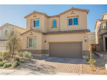 Two-story tan home with a two-car garage, desert landscaping and a brick driveway at 10415 Andele Ave, Las Vegas, NV 89166
