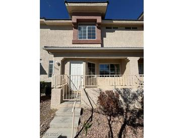 A tan two-story townhouse featuring a small porch area with stairs leading to the front door at 1308 Dusty Creek St, Las Vegas, NV 89128