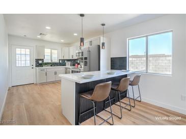 Bright kitchen features white cabinets, modern appliances, and an island with bar seating at 1945 Margarita Ave, Henderson, NV 89011