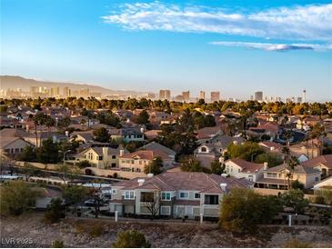 An elevated view of a neighborhood with a sprawling cityscape and mountain range in the distance on a clear, sunny day at 2325 Windmill Pkwy # 1711, Henderson, NV 89074